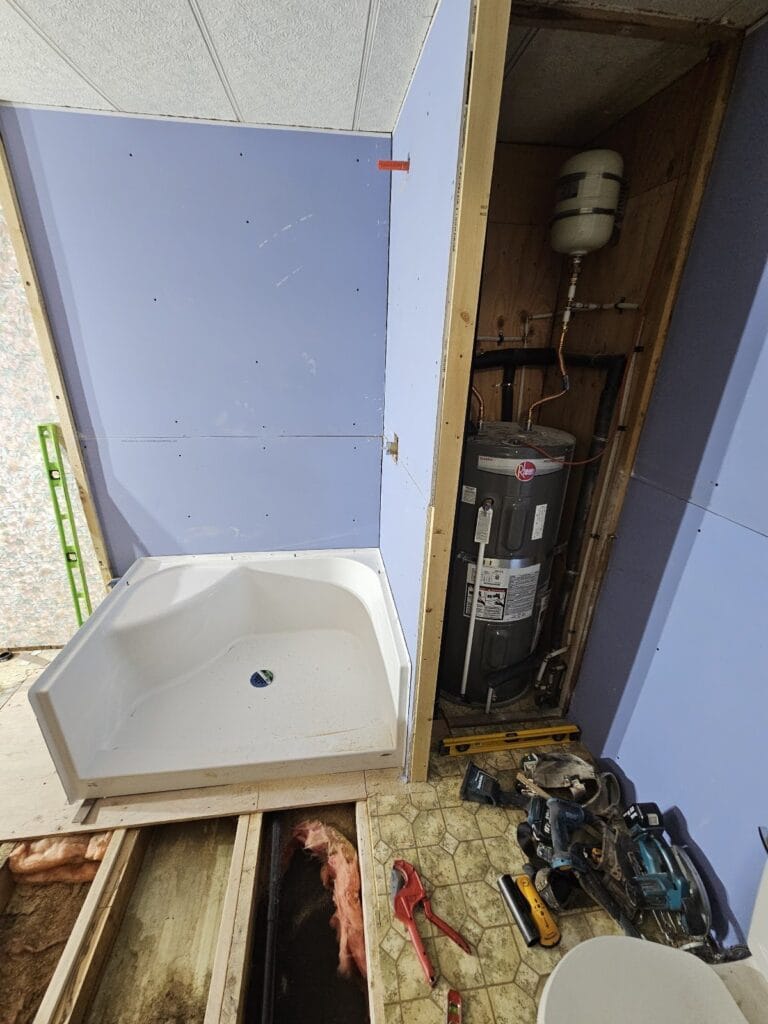 New shower base set next to the water heater closet