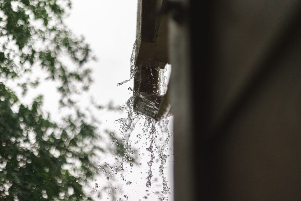 Rainwater pouring from a house gutter during heavy autumn rain