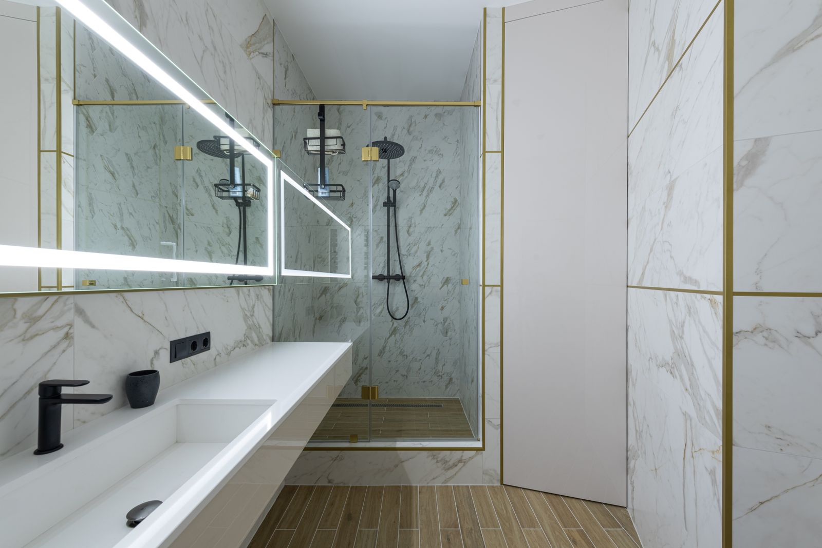 Marble bathroom with a long vanity, an illuminated mirror and a glass shower